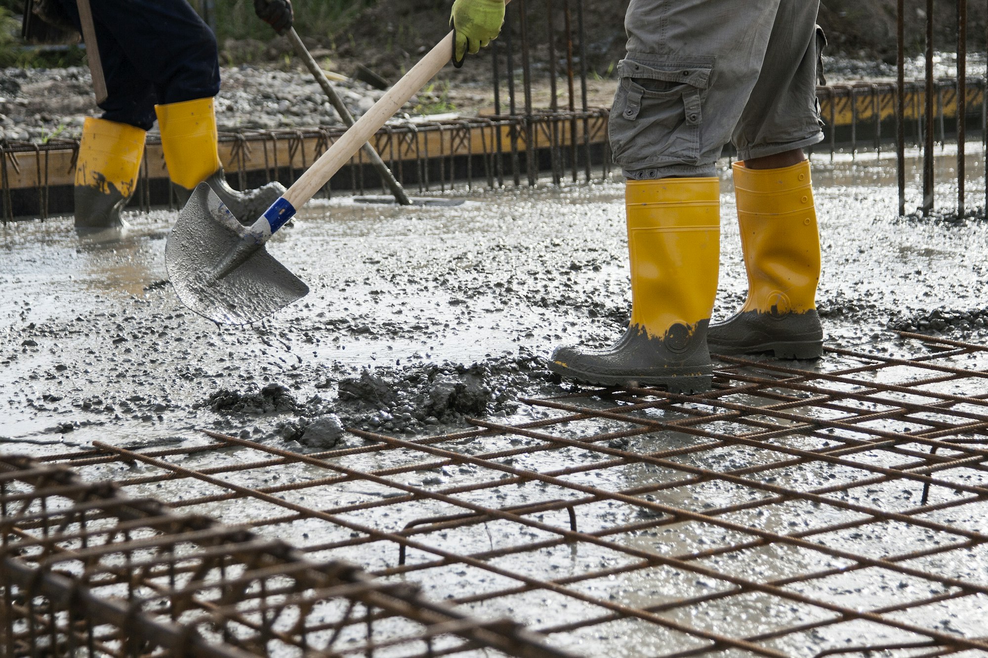 two bricklayers who level the freshly poured concrete to lay the foundations of a building